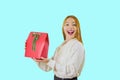 A beautiful sweet red-haired girl in a white blouse holds a gift bag a box of red with a green velvet ribbon raising the Royalty Free Stock Photo