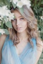 Beautiful sweet tender girl with blue eyes in a blue dress with light hair stranded in jasmine flowers Royalty Free Stock Photo