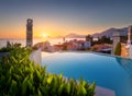 Beautiful swimming pool, green bush and orange roofs at sunset