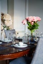 A beautiful table served with dishes and a bouquet of roses.