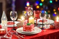 Beautiful table setting for Christmas party or New Year celebration at home. Cozy room with a fireplace and Christmas tree in a ba Royalty Free Stock Photo