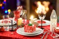 Beautiful table setting for Christmas party or New Year celebration at home. Cozy room with a fireplace and Christmas tree in a ba Royalty Free Stock Photo