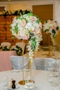 Beautiful table setting with crockery and white flower arrangements in a vase on a high stem for a party, wedding reception or Royalty Free Stock Photo