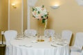 Beautiful table setting with crockery and white flower arrangements in a vase on a high stem for a party, wedding reception or Royalty Free Stock Photo