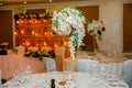 Beautiful table setting with crockery and white flower arrangements in a vase on a high stem for a party, wedding reception or Royalty Free Stock Photo