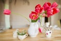 Beautiful table setting with red tulips, forget-me-not and cups on the wooden table