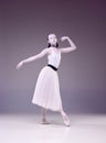 Beautiful talented young woman, professional ballerina, in image of porcelain statue dancing over studio background.