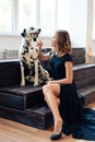 Beautiful tall girl in black dress with dog Dalmatian in studio