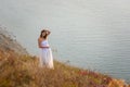 A beautiful tall slender girl stands on a hill by the sea