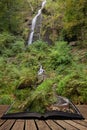 Beautiful tall waterfall flowing over lush green landscape foliage in early Autumn coming out of pages of open story book