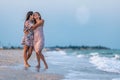 A girl in a dress hugs her mom in a dress while walking along the beach near the sea with waves Royalty Free Stock Photo