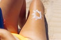 Beautiful tanned female legs on the beach, close-up, the sun is drawn on the leg with white sunscreen Royalty Free Stock Photo