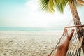 Beautiful Tanned legs of women. relax on hammock at sandy tropical beach Royalty Free Stock Photo