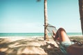 Beautiful Tanned legs of women. relax on hammock at sandy tropical beach. Royalty Free Stock Photo