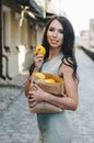 A beautiful, tanned, sexy southern beauty stands on a motley background surrounded by palm leaves and holds a wooden bowl with