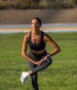 Beautiful, tanned young sporty girl with long dark hair, bending over and crossing her leg touching it with her hands to warm up Royalty Free Stock Photo