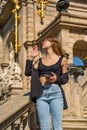 Beautiful tanned young woman in a black top and jeans and loose hair holding her mobile phone with her hand and closing her eyes Royalty Free Stock Photo