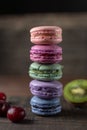 Beautiful and tasty French macaroon cookies stand on a wooden stand next to the fruit. Romantic dinner in the back of the house.