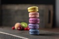 Beautiful and tasty French macaroon cookies stand on a wooden stand next to the fruit. Romantic dinner in the back of the house.