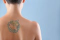 Beautiful tattoo on female back against color background