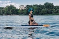 beautiful tattooed woman with blue hair sitting on sup board