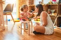 Beautiful teacher and blond student toddler girl playing with dinosaurs at kindergarten Royalty Free Stock Photo