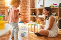 Beautiful teacher and blond student toddler girl playing with dinosaurs at kindergarten Royalty Free Stock Photo