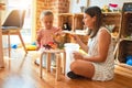 Beautiful teacher and blond student toddler girl playing with dinosaurs at kindergarten Royalty Free Stock Photo