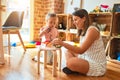 Beautiful teacher and blond student toddler girl playing with dinosaurs at kindergarten Royalty Free Stock Photo