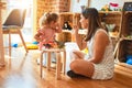 Beautiful teacher and blond student toddler girl playing with dinosaurs at kindergarten Royalty Free Stock Photo