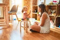 Beautiful teacher and blond student toddler girl playing with dinosaurs at kindergarten Royalty Free Stock Photo