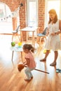 Beautiful teacher and blond student toddler girl ridding horse toy with stick at kindergarten