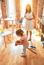 Beautiful teacher and blond student toddler girl ridding horse toy with stick at kindergarten