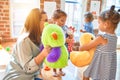 Beautiful teacher and group of toddlers playing around lots of toys at kindergarten