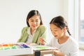 beautiful teacher happy, smile, look at young child fun painting color in education classroom, select focus at teacher. asian Royalty Free Stock Photo