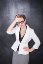 Beautiful teacher with headache on blackboard background