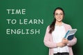 Teacher near green chalkboard with text Time To Learn English Royalty Free Stock Photo