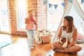 Beautiful teacher sitting on the floor getting angry with blond toddler girl outside tipi at kindergarten Royalty Free Stock Photo