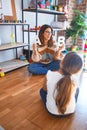 Beautiful teacher teaching toddler alphabet around lots of toys at kindergarten