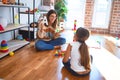 Beautiful teacher teaching toddler alphabet around lots of toys at kindergarten