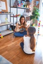 Beautiful teacher teaching toddler alphabet around lots of toys at kindergarten