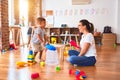 Beautiful teacher and toddler boy playing drum using skitlle and plastic basket at kindergarten Royalty Free Stock Photo