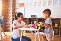 Beautiful teacher and toddler boy playing with tractor and cars at kindergarten