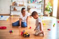 Beautiful teacher and toddler boy playing with tractor and cars at kindergarten