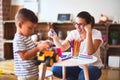 Beautiful teacher and toddler boy playing with tractor and cars at kindergarten