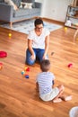 Beautiful teacher and toddler boy playing with tractor and cars at kindergarten