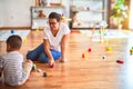 Beautiful teacher and toddler boy playing with tractor and cars at kindergarten