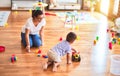 Beautiful teacher and toddler boy playing with tractor and cars at kindergarten