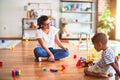 Beautiful teacher and toddler boy playing with tractor and cars at kindergarten