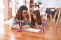 Beautiful teacher and toddler drawing using pencils and paper around lots of toys at kindergarten Royalty Free Stock Photo